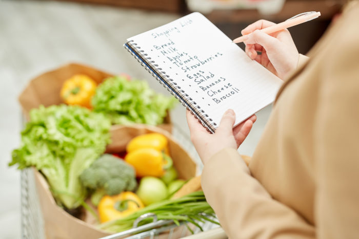 A person using a grocery shopping list in a store.