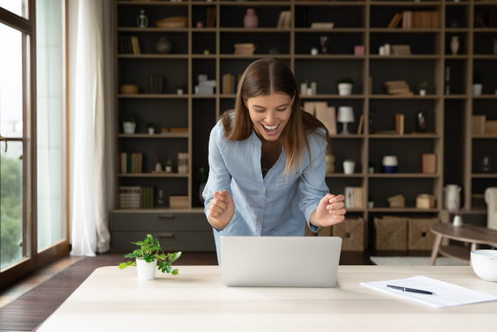 A woman is very happy and excited about something that she has setup on her laptop computer.