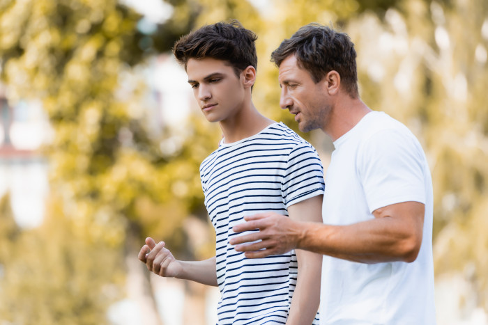 A father talking to his teenage son who is a young adult about paying rent.