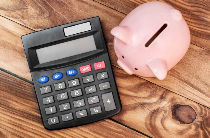 A calculator and a piggy bank representing an alternative budgeting tool for tracking money through income and expenses.